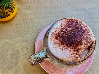 A beautiful cup of cappuccino with milk foam and chocolate sprinkled on it;  orange juice in beautiful jars; bright plate; nuts; healthy food 