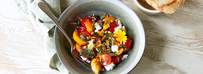 bowl of salad with nectarines, tomatoes and feta cheese on a light table