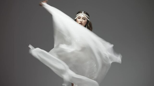 The belly and body of a woman dancing oriental dance in the studio, making beautiful body movements, she is dressed in a chic costume. The concept of dances, oriental women and plastic arts.