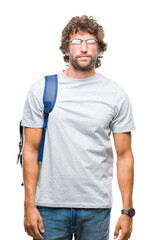 Handsome hispanic student man wearing backpack and glasses over isolated background with serious expression on face. Simple and natural looking at the camera.