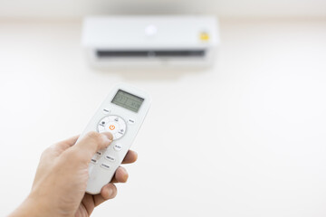 Air conditioner with remote controller. Hand of a man adjusting temperature on air conditioner with remote control