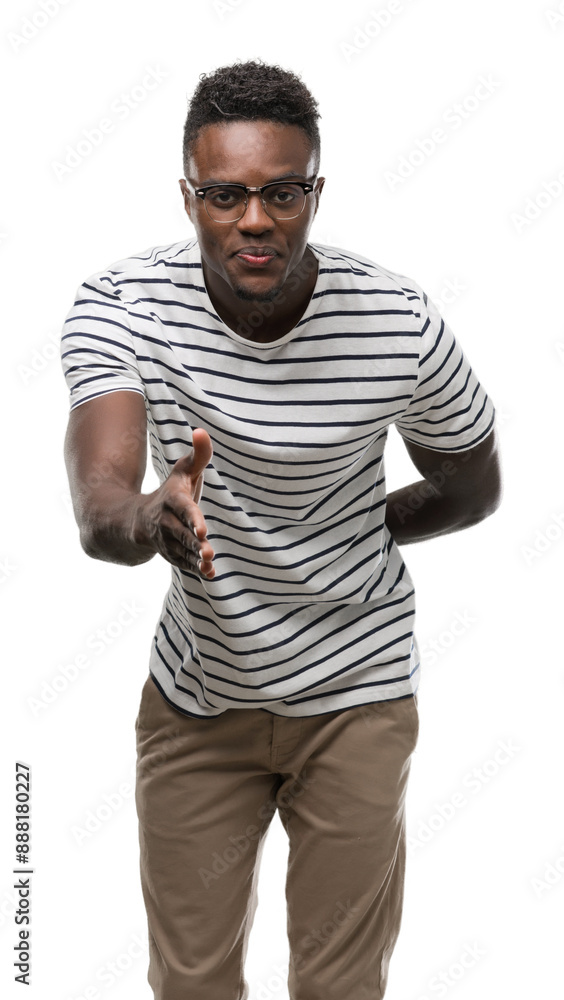 Sticker Young african american man wearing glasses and navy t-shirt smiling friendly offering handshake as greeting and welcoming. Successful business.