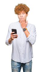 Fototapeta premium Young handsome man using smartphone cover mouth with hand shocked with shame for mistake, expression of fear, scared in silence, secret concept