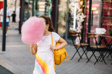 Cute little girl eating cotton candy. Happy childhood. Summer holidays concept.