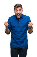 Fototapeta premium Young handsome man over isolated background celebrating surprised and amazed for success with arms raised and open eyes. Winner concept.