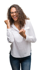 Beautiful young hispanic woman very happy and excited doing winner gesture with arms raised, smiling and screaming for success. Celebration concept.