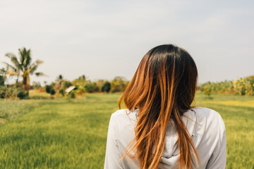 Asian woman resting at the rice fields after working out in the morning.