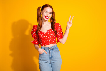 Photo portrait of pretty young girl show v-sign wear trendy red outfit isolated on yellow color background