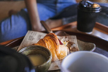 Part close up of woman is having a croissant and coffee.