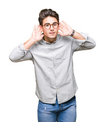 Young handsome man wearing glasses over isolated background Trying to hear both hands on ear gesture, curious for gossip. Hearing problem, deaf