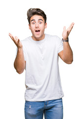 Fototapeta premium Young handsome man wearing white t-shirt over isolated background celebrating crazy and amazed for success with arms raised and open eyes screaming excited. Winner concept
