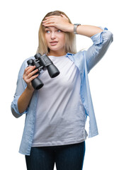 Young caucasian woman holding binoculars over isolated background stressed with hand on head, shocked with shame and surprise face, angry and frustrated. Fear and upset for mistake.