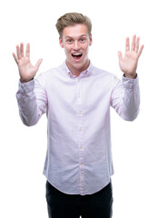 Young handsome blond man very happy and excited, winner expression celebrating victory screaming with big smile and raised hands