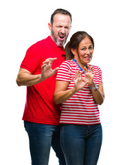 Fototapeta premium Middle age hispanic couple in love over isolated background disgusted expression, displeased and fearful doing disgust face because aversion reaction. With hands raised. Annoying concept.
