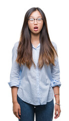 Young asian business woman wearing glasses over isolated background afraid and shocked with surprise expression, fear and excited face.