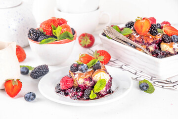 Homemade sweet berry cobbler pie cake with various garden forest berries - strawberry, blackberry, blueberry, healthy summer dessert recipe in baking pan and plate, copy space