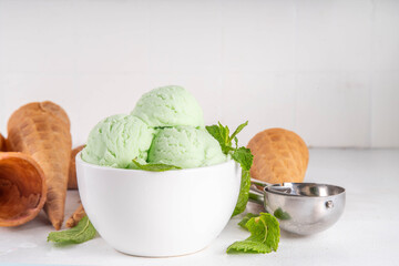 Green mint or melissa homemade ice cream, refreshing sweet sorbet dessert in serving bowl, with...