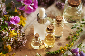 Bottles of aromatherapy essential oil with summer flowers