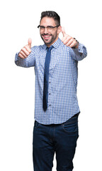 Fototapeta premium Young business man wearing glasses over isolated background approving doing positive gesture with hand, thumbs up smiling and happy for success. Looking at the camera, winner gesture.