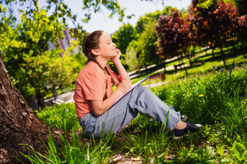 Full size photo of charming lovely little girl summer play outside good mood sit under tree homework enjoy free time weekend outdoors