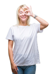 Fototapeta premium Young beautiful blonde woman wearing white t-shirt over isolated background doing ok gesture with hand smiling, eye looking through fingers with happy face.