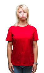 Young beautiful blonde woman wearing red t-shirt over isolated background puffing cheeks with funny face. Mouth inflated with air, crazy expression.