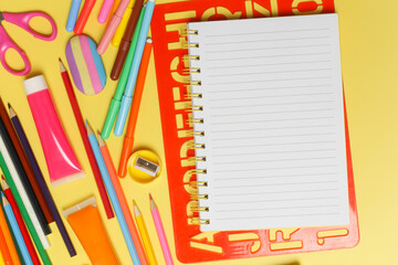 Back to school concept with variety of office and school supplies on yellow background.	