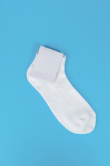 Pair of white socks with blank labels on blue background. Mock up with blank label