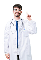 Fototapeta premium Young doctor man wearing hospital coat over isolated background showing and pointing up with finger number one while smiling confident and happy.
