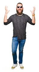 Naklejka premium Young hipster man wearing sunglasses celebrating crazy and amazed for success with arms raised and open eyes screaming excited. Winner concept