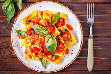 Ravioli with tomato sauce and basil on dark background.