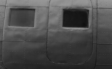 The fuselage of an old military airplane with doors and an illuminator.