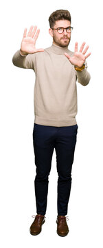 Young handsome business man wearing glasses Smiling doing frame using hands palms and fingers, camera perspective