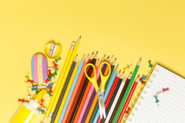 Back to school concept with variety of office and school supplies on yellow background.
