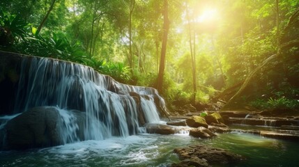 Obraz premium Forest waterfall flowing through lush greenery in summer, with sunlight filtering through trees