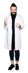 Fototapeta premium Doctor therapist man with long hair and bear wearing white coat angry and mad raising fist frustrated and furious while shouting with anger. Rage and aggressive concept.