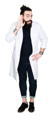 Doctor therapist man with long hair and bear wearing white coat smiling with hand over ear listening an hearing to rumor or gossip. Deafness concept.