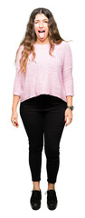 Fototapeta premium Young beautiful woman wearing pink sweater sticking tongue out happy with funny expression. Emotion concept.