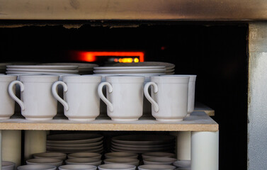 New ceramic identical white dishes sent to a muffle kiln for firing at a porcelain factory in the...