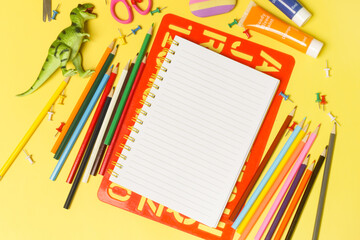 Back to school concept with variety of office and school supplies on yellow background.