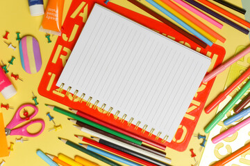 Back to school concept with variety of office and school supplies on yellow background.