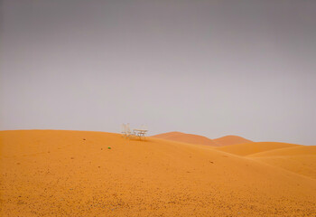 A lonely small metal table with chair on the dune in the middle of the Sahara desert in Merzougha, Morocco