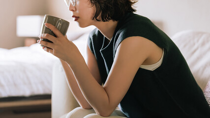 ソファで飲み物を飲む日本人女性