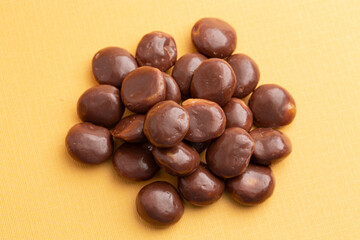 Sweet Chocolate Covered Caramel Disks on Yellow Background