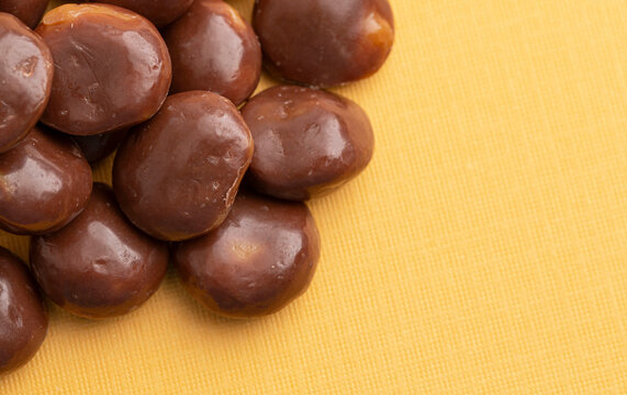 Sweet Chocolate Covered Caramel Disks on Yellow Background