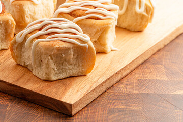 Drizzled Homemade Bready Cinnamon Roll Buns on a Wood Board