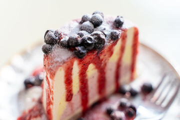 beautiful blueberry cheesecake with strawberry sauce and berries on a plate. Exquisite presentation. Selected focus