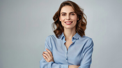 A Confident Woman Standing Against a Grey Wall, Arms Crossed, With a Soft Smile
