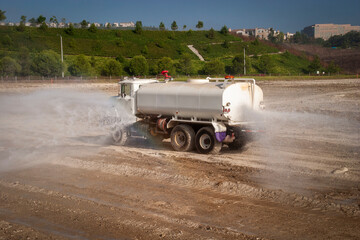 A water truck spraying down dirt at a construction site 