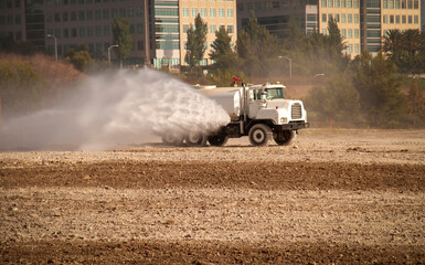 A water truck spraying down dirt at a construction site
